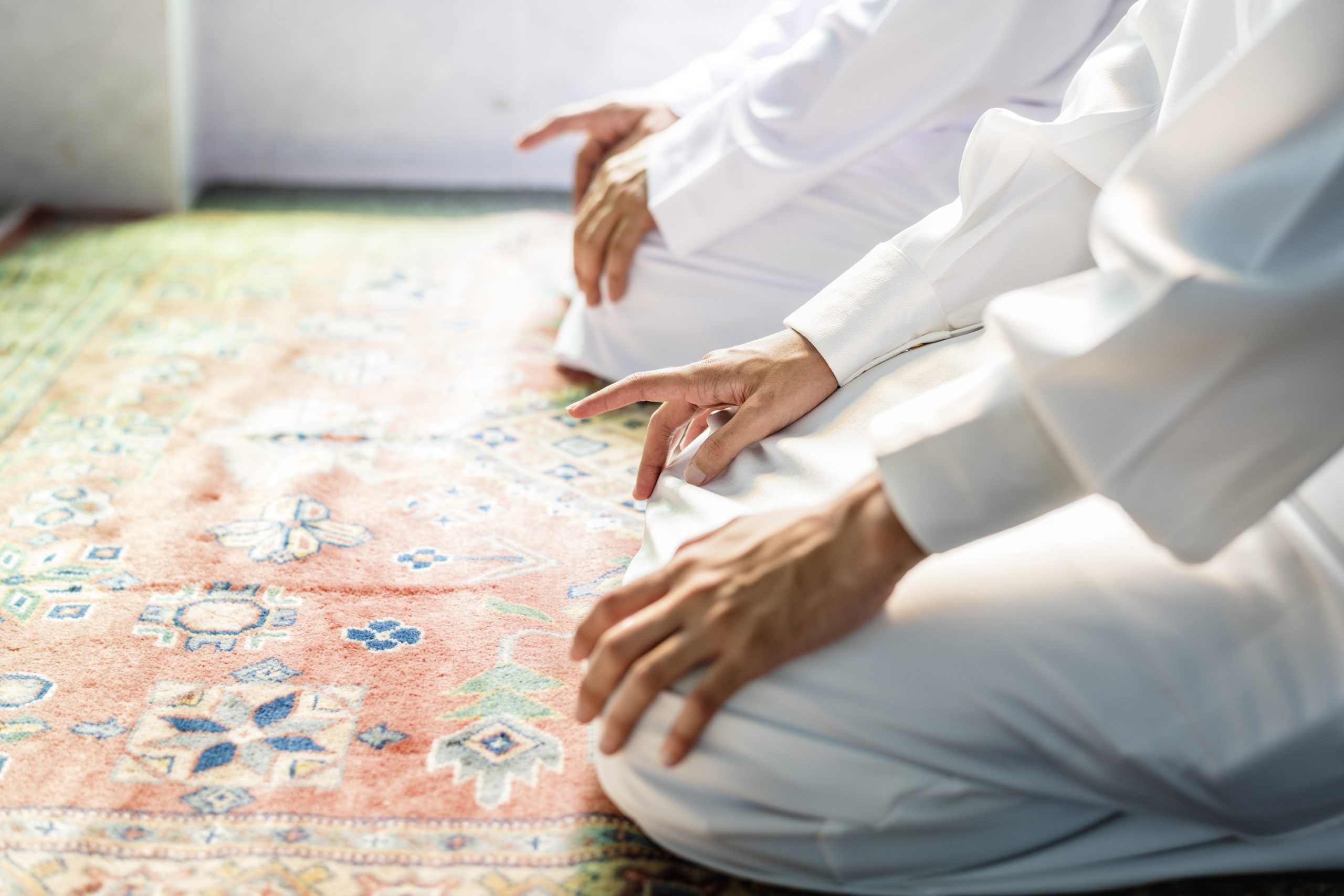 Muslim men praying in Tashahhud posture